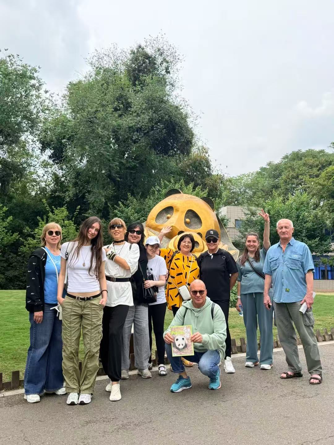 Tour group posing in front of the golden panda statue at Chengdu Panda Base